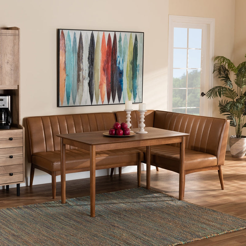 Cozy dining nook with a wooden rectangular table, brown leather upholstered corner bench seating, and modern décor including a colorful abstract wall art, candles, and a bowl of red apples