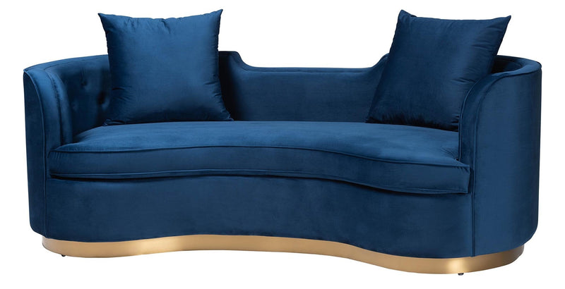 Modern blue velvet sofa with curved design, gold base, and matching cushions.